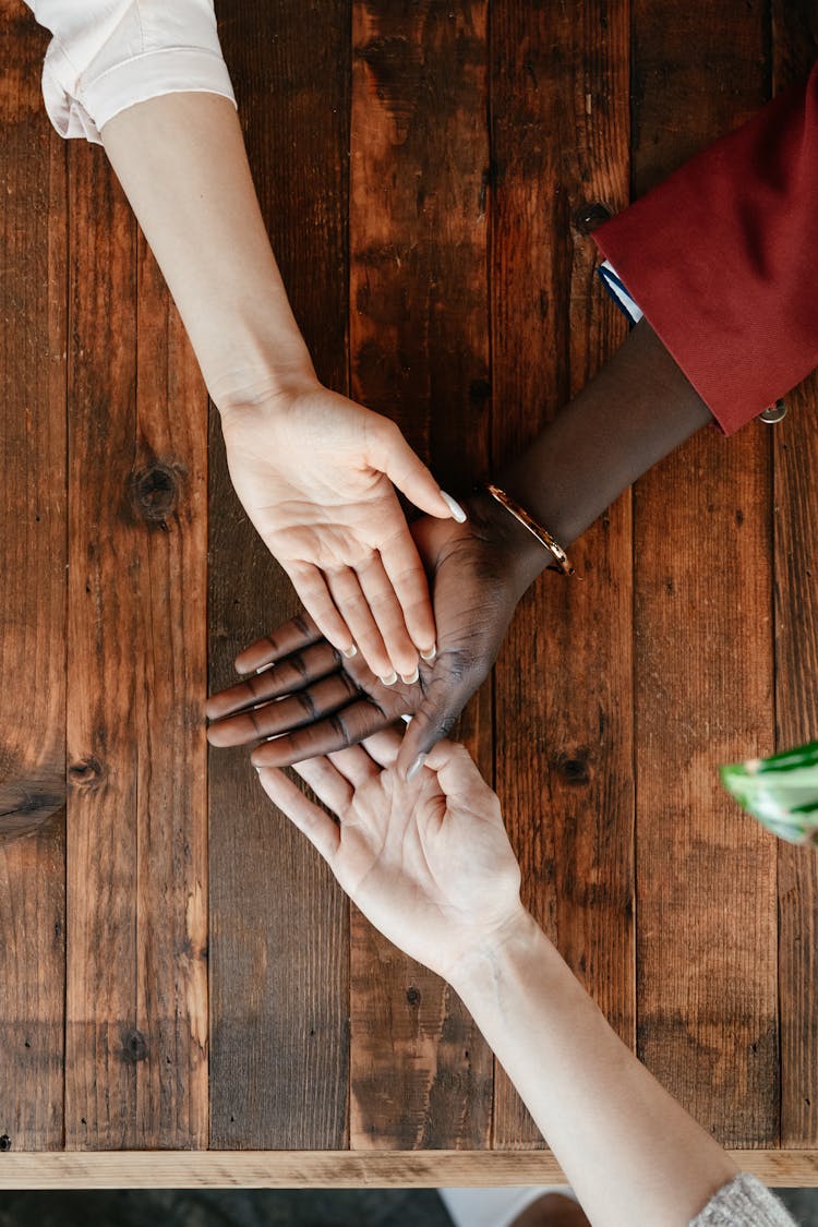 Multiethnic Best Friends Stacking Hands On Timber Table