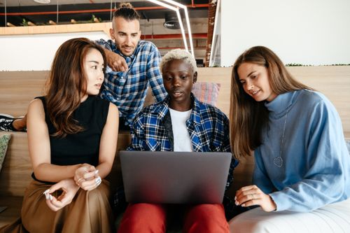 Free Group of multiracial young business colleagues discussing strategy while using netbook in modern workspace Stock Photo