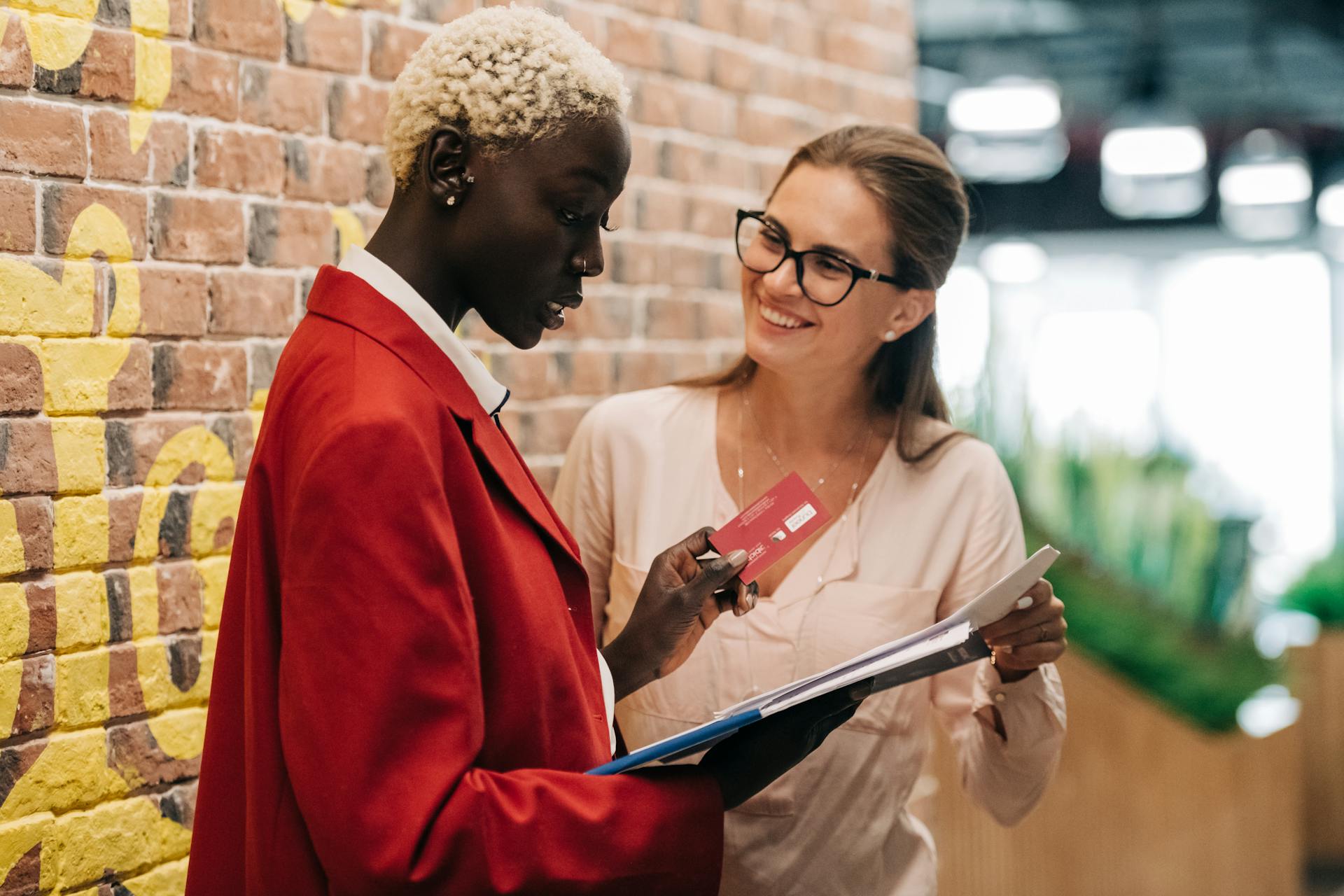 Diverse elegant business colleagues talking about important contract near brick wall of modern office