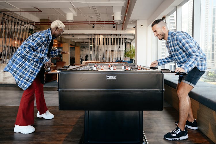 Cheerful Diverse Friends Playing Foosball In Living Room