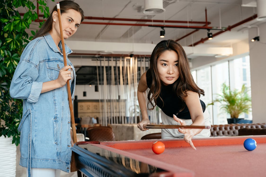 Diverse friends playing billiard at home