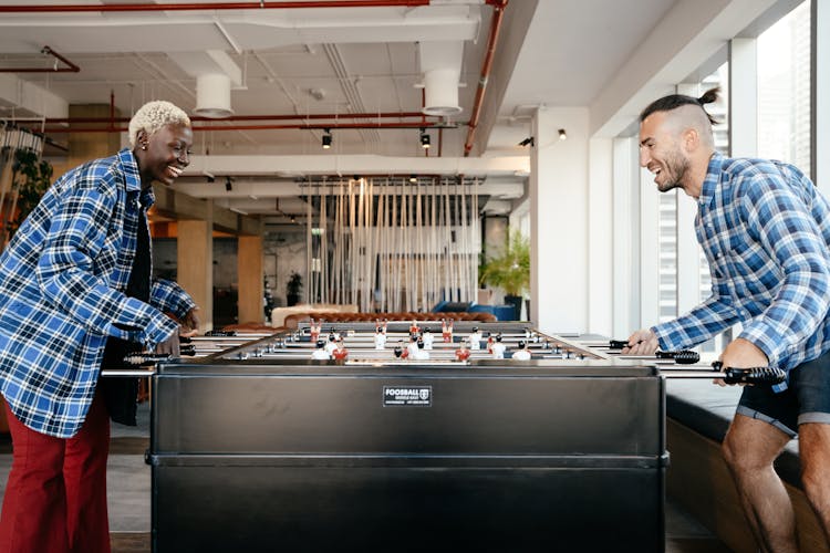 Happy Multiracial Couple Playing In Foosball At Home