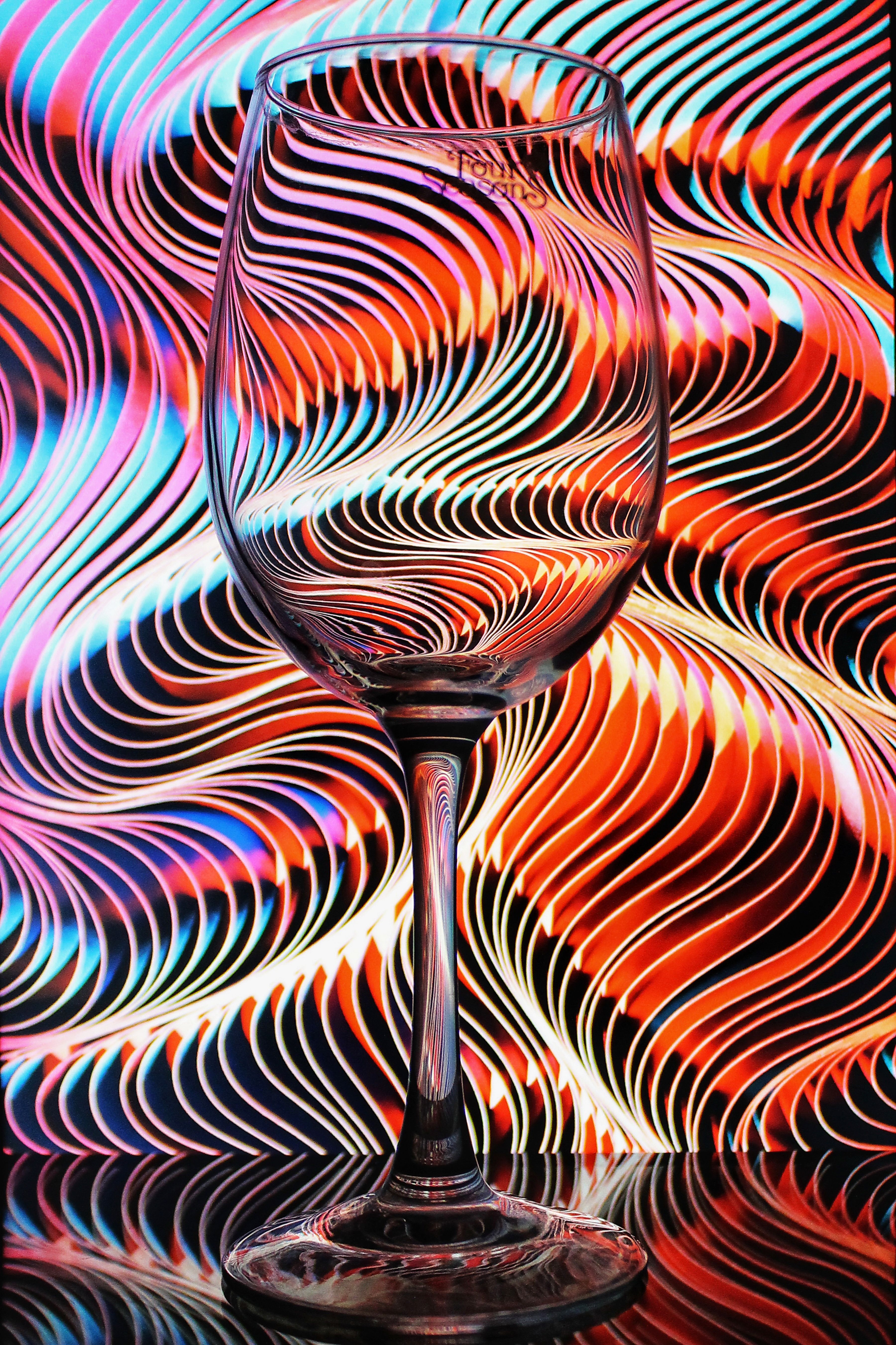 Close-up of a clear wine glass with a vibrant, wavy pattern in the background.