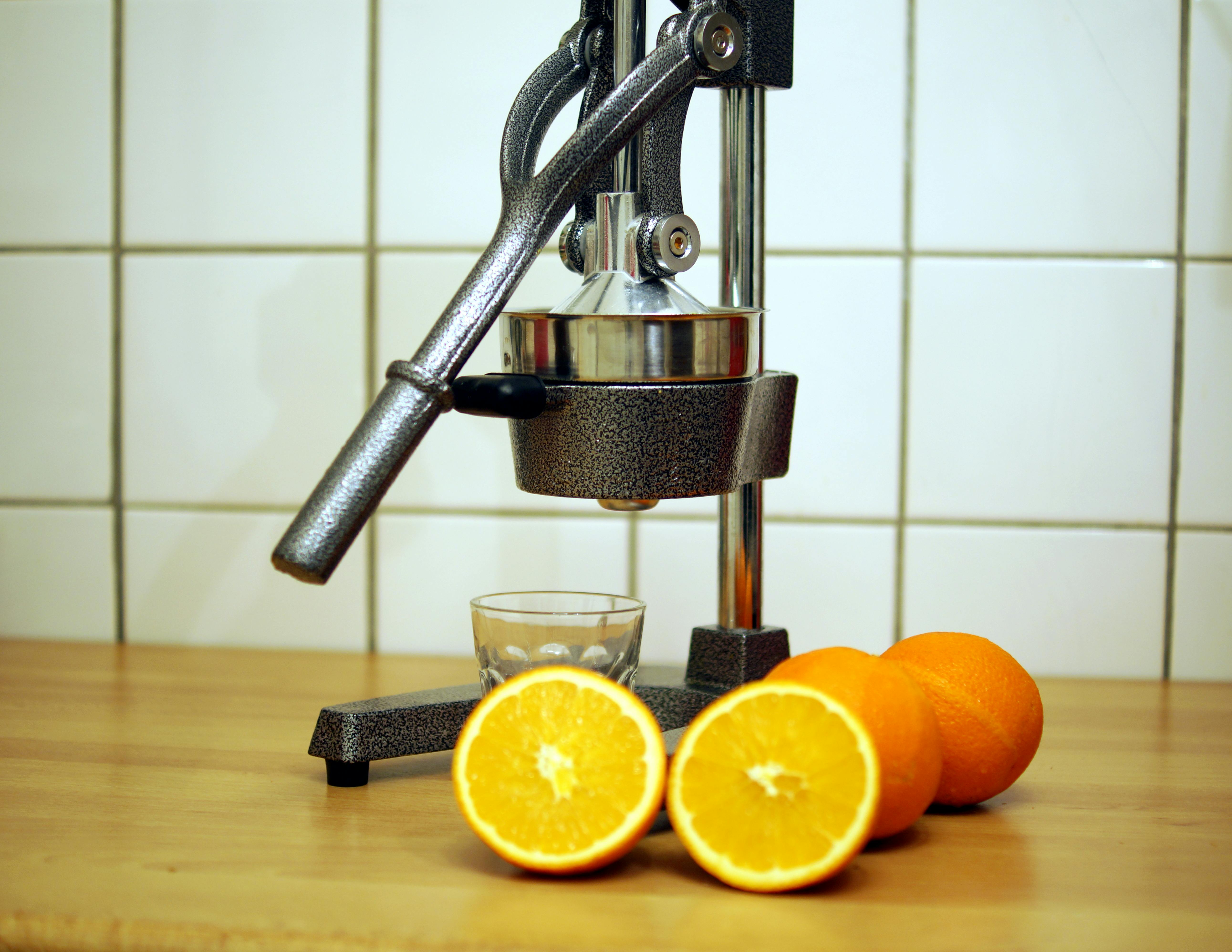a close up shot of oranges beside a juicer