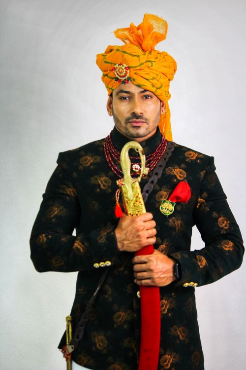 Free Elegant Indian groom in traditional Rajput attire holding a sword, showcasing cultural heritage. Stock Photo