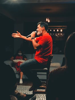 Middle-aged male singer performing indoors with microphone, engaging audience.