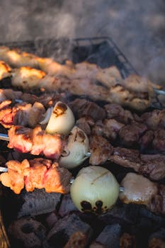 Close-up of assorted skewers grilling over charcoal, featuring onions and meats.