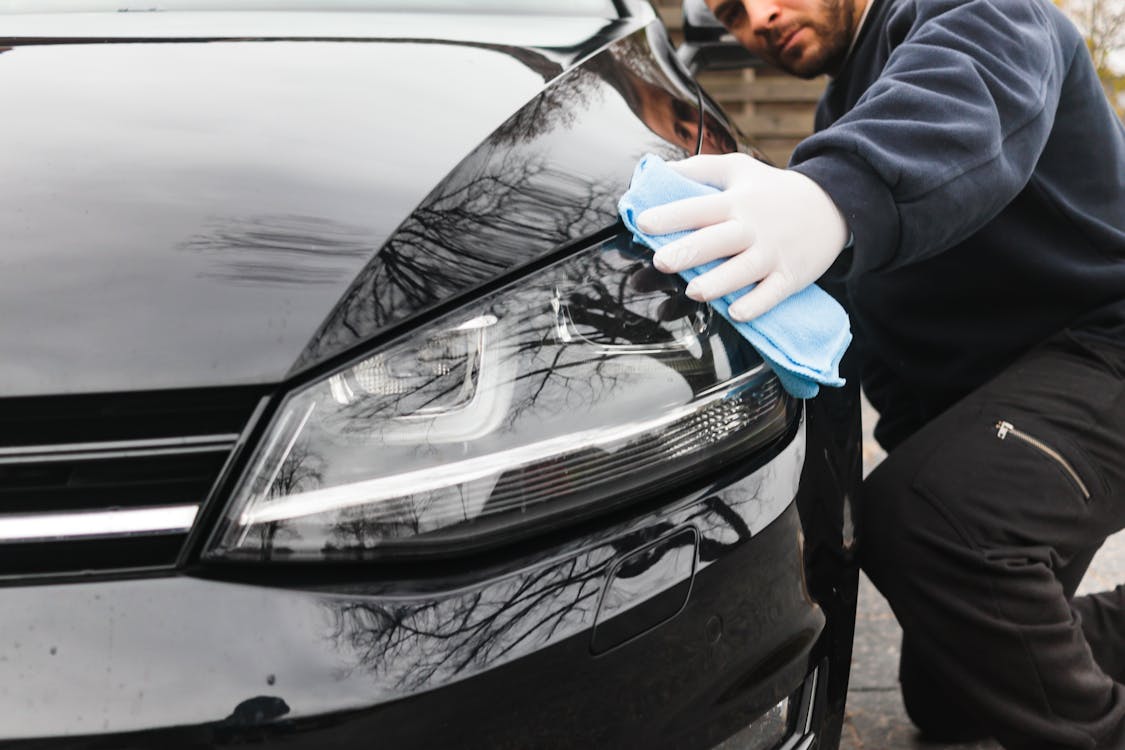 A detailer is wiping a car's headlights