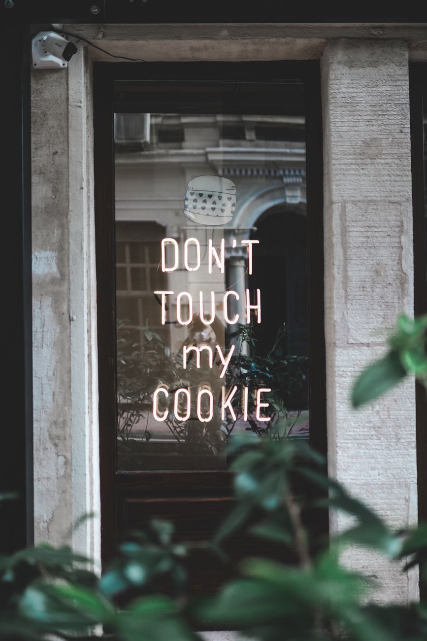 Window of modern restaurant with neon luminous inscription on urban street in daytime