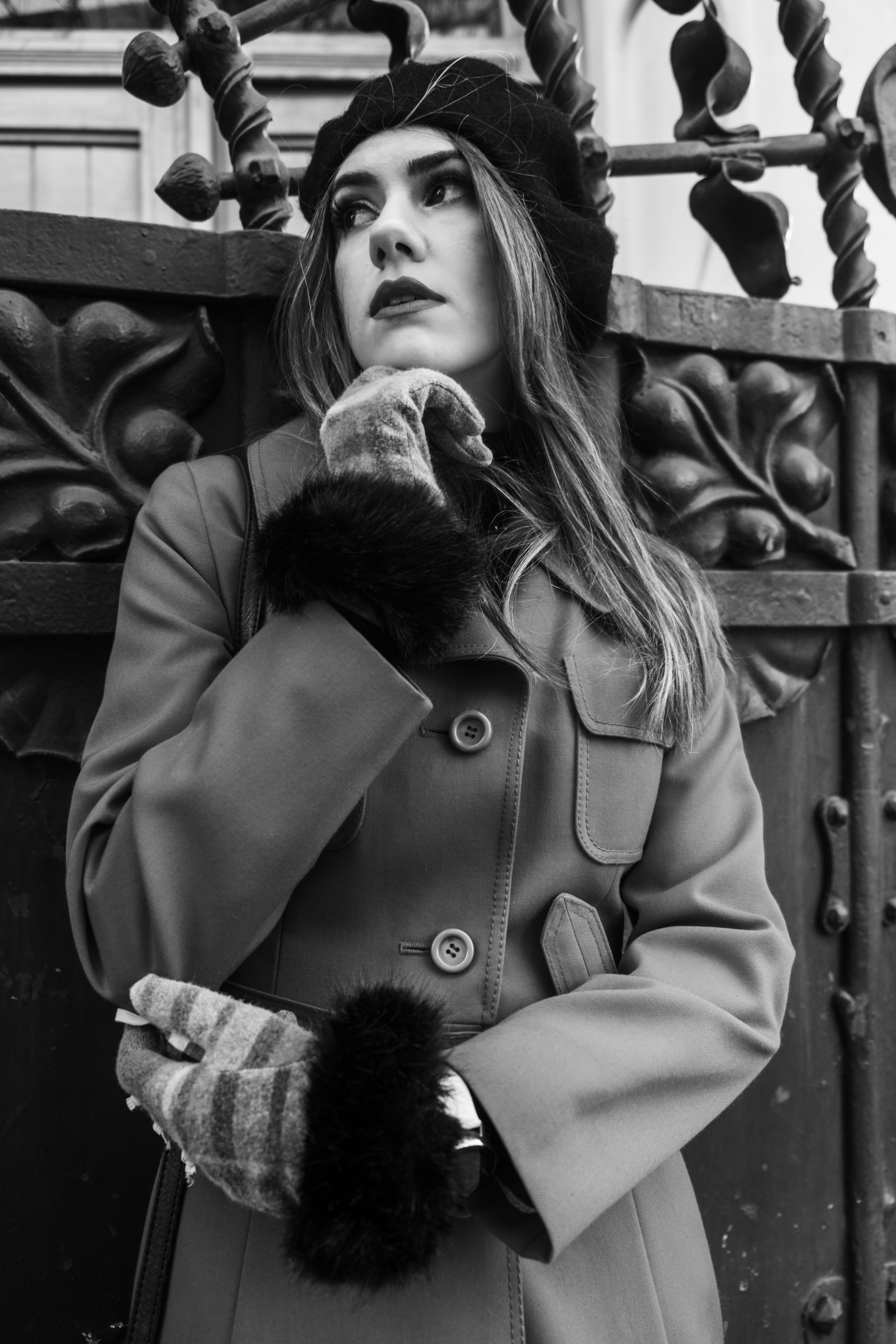 Elegant black and white portrait of a fashionable woman in a coat and beret.