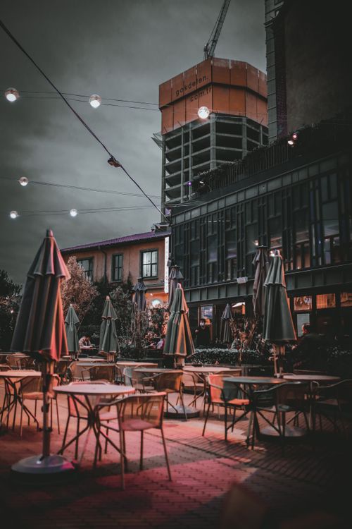 Free Contemporary street cafe with closed umbrellas under garland with lights in dusky evening Stock Photo