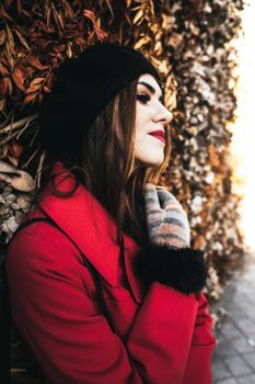 Fashionable woman in red coat and beret, captured outdoors in a stylish portrait.