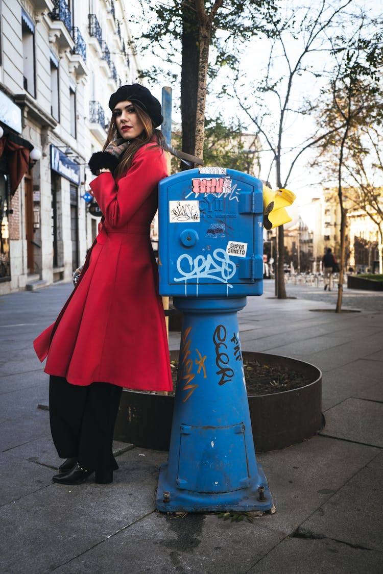 Woman In Red Coat Standing Beside A Postbox