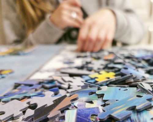 Free Hands working on a colorful jigsaw puzzle, showcasing leisure and concentration. Stock Photo