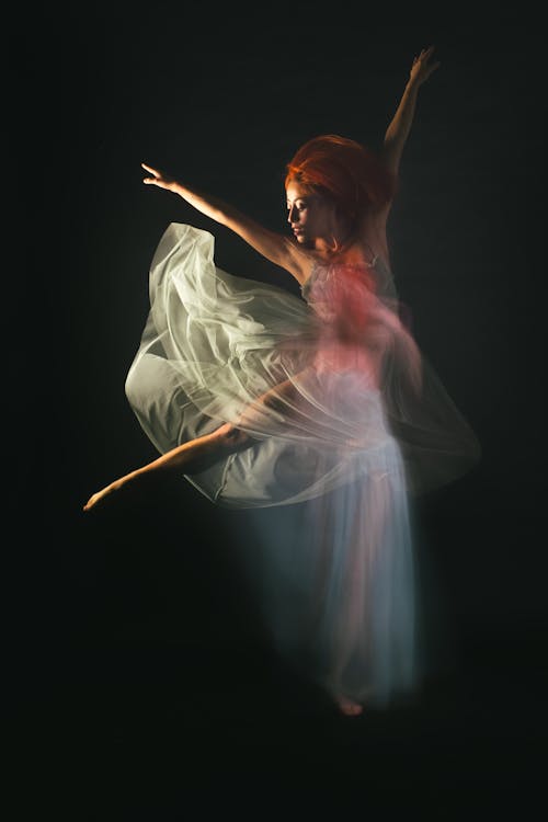 A Woman in White Dress Dancing Gracefully