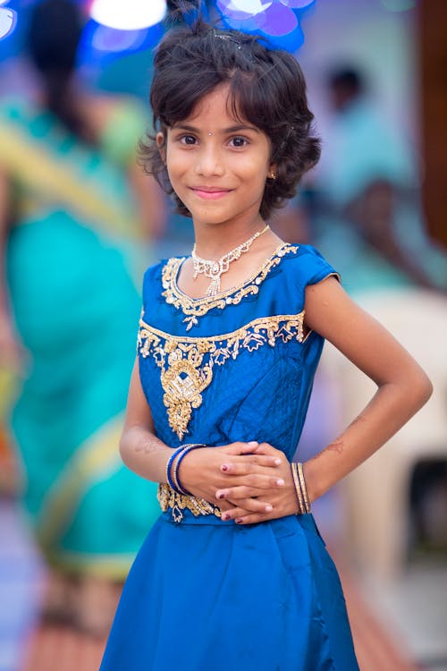 A Girl in Blue Traditional Dress Smiling while Looking at Camera