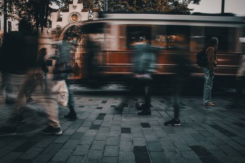 Free Blurred unrecognizable pedestrians walking on paved street near aged tramway in motion in old city Stock Photo