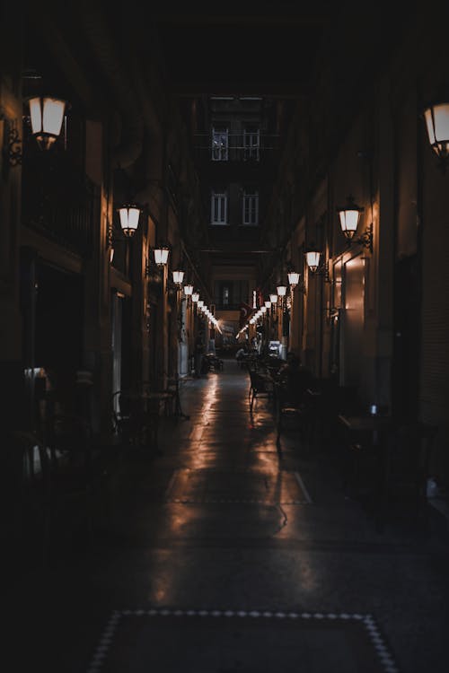 Dark narrow street amidst old residential buildings and vintage lanterns