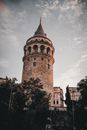 From below of aged famous Galata Tower with arched windows and sharp roof located in Istanbul against cloudy sky