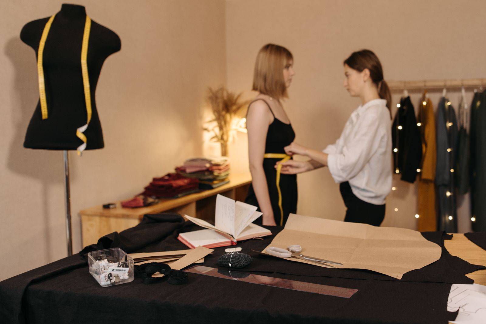 Schneiderin nimmt Maße in einem hellen Atelier