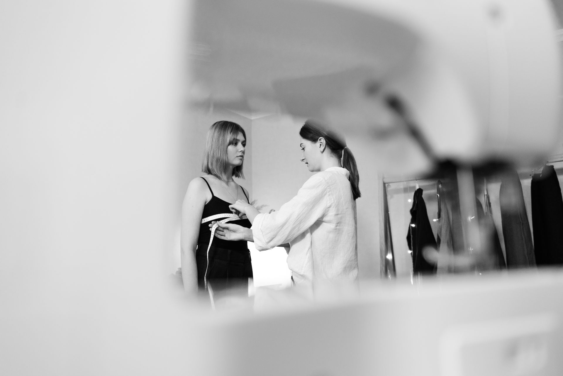 Grayscale Photo of a Seamstress Measuring her Client
