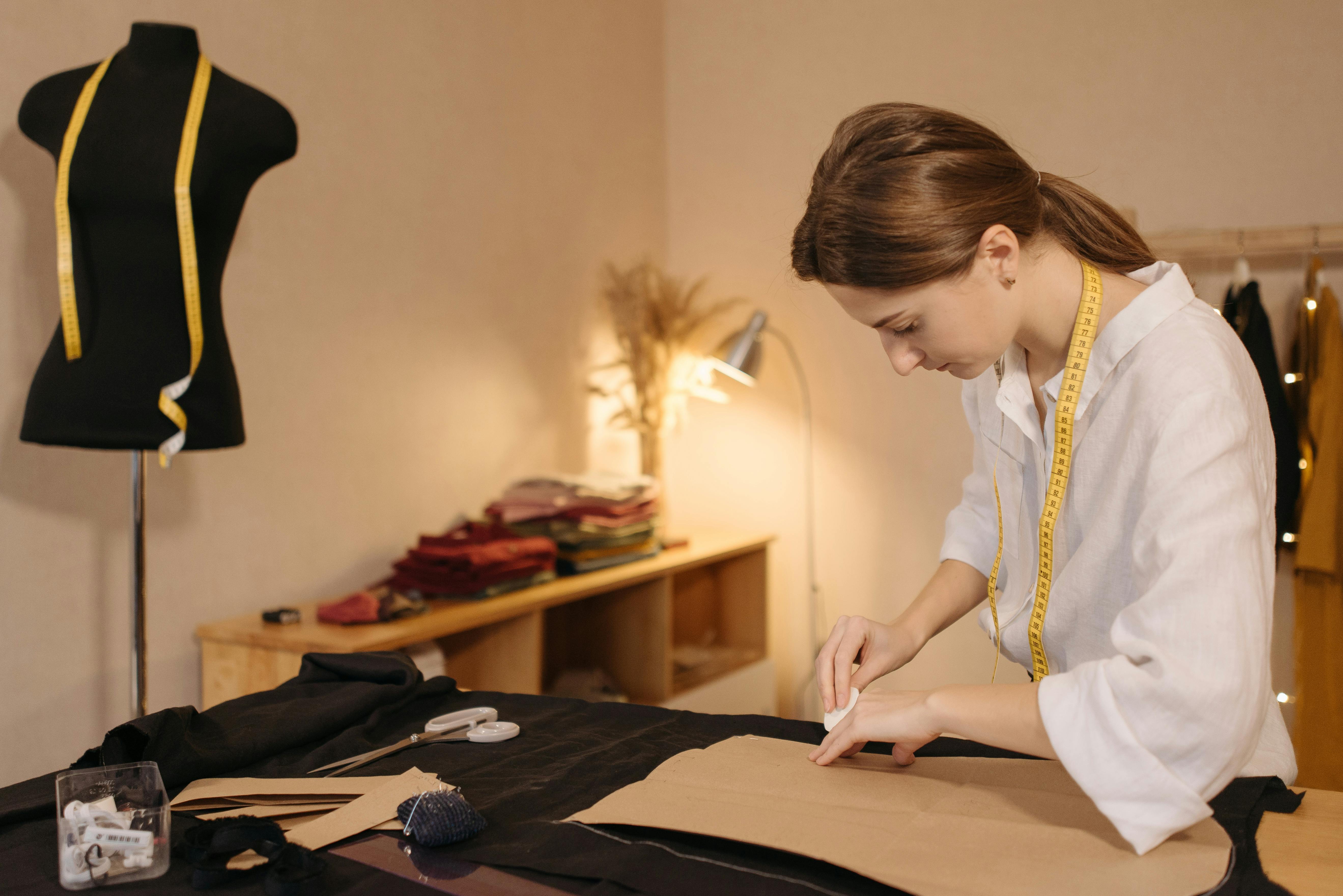 Caucasian dressmaker measuring and tailoring fabric in a fashion studio.