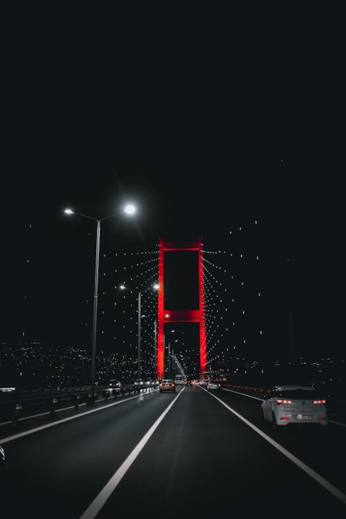 Vehicles driving on illuminated bridge under night sky