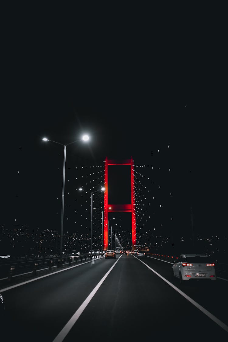 Vehicles Driving On Illuminated Bridge Under Night Sky