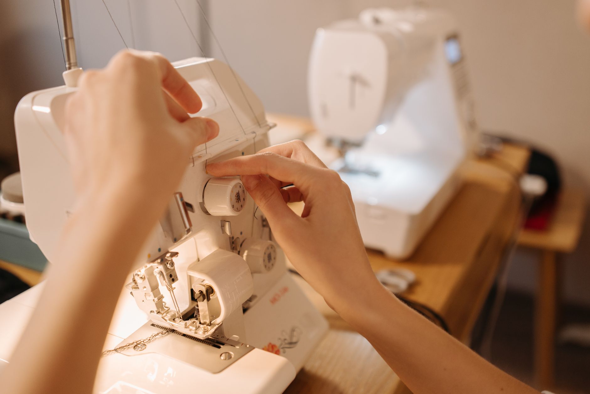 Mãos ajustando os botões de uma máquina de costura para costura precisa. Perfeito para visuais relacionados a costura, artesanato ou hobbies.