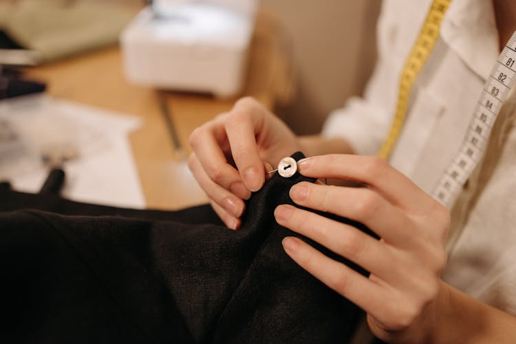 Person Sewing The Button On The Black Cloth 