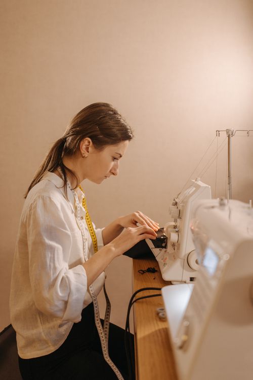 Free A focused seamstress using a sewing machine in a workshop setting. Stock Photo