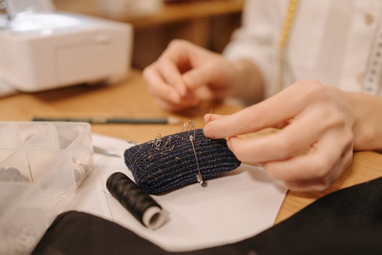 Dressmaker Putting Pins And Needles On Cushion