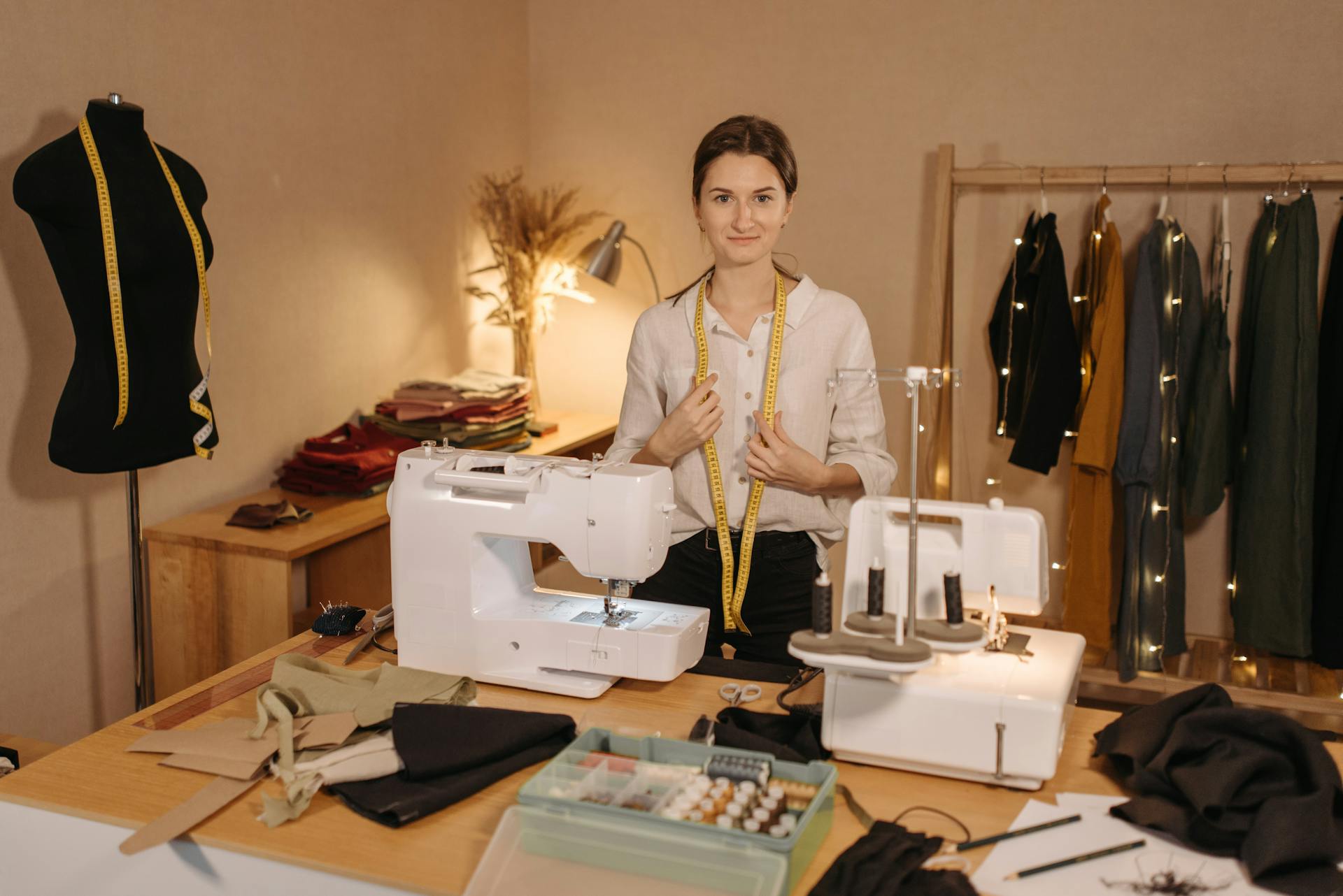 Adult woman with measuring tape in a sewing room with machines and fabrics.