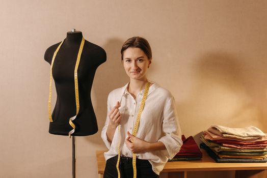 Dressmaker Smiling in White Long Sleeve Blouse Standing Beside Black Manikin with Measuring Tape Hanging on Her Neck