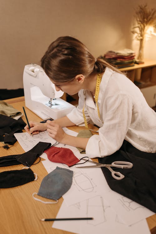 Dressmaker in White Long Sleeve Polo Shirt Sketching a Pattern on Paper