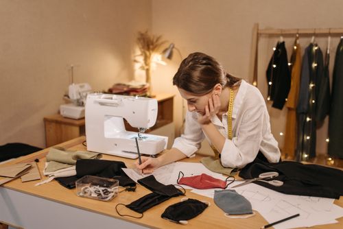 Free A woman tailor designs fabric face masks in a cozy workshop setting. Stock Photo