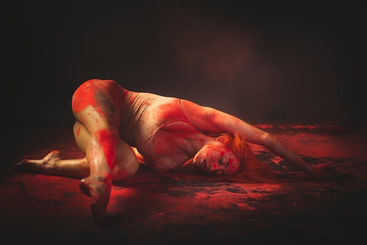 A Woman Lying On The Floor With Red Paint On Her Body