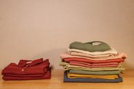 Neatly folded colorful clothes on a wooden table, showcasing texture and style.