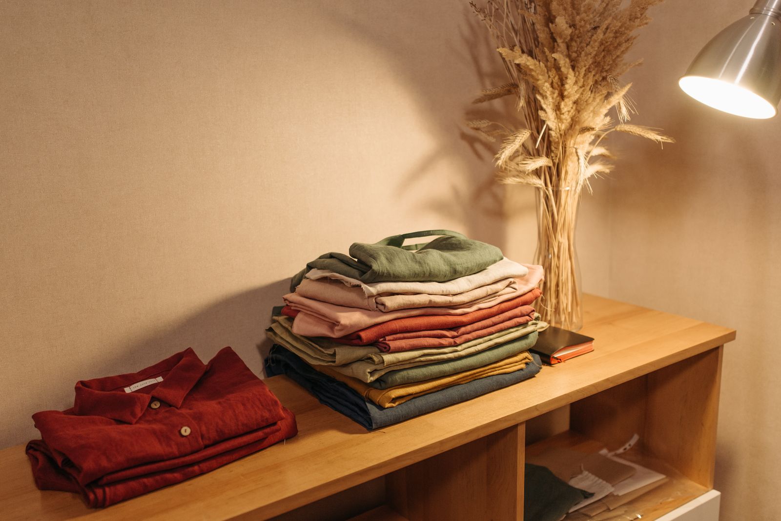 Folded linen clothing on wooden table with warm lighting and no people