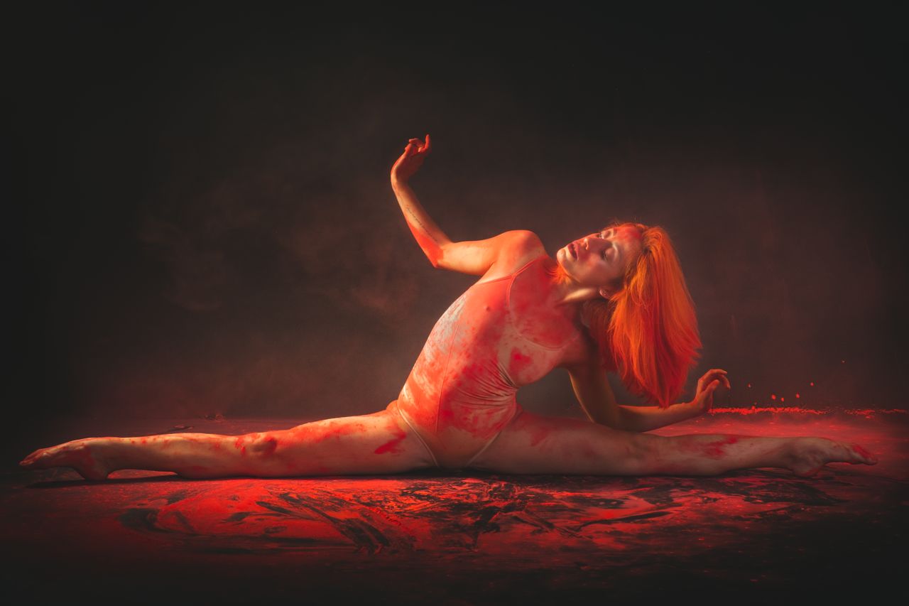 contemporary dancer in a bodysuit performs a split surrounded by vibra