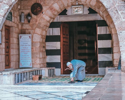 Man Leaving Shoes by Mosque Entrance