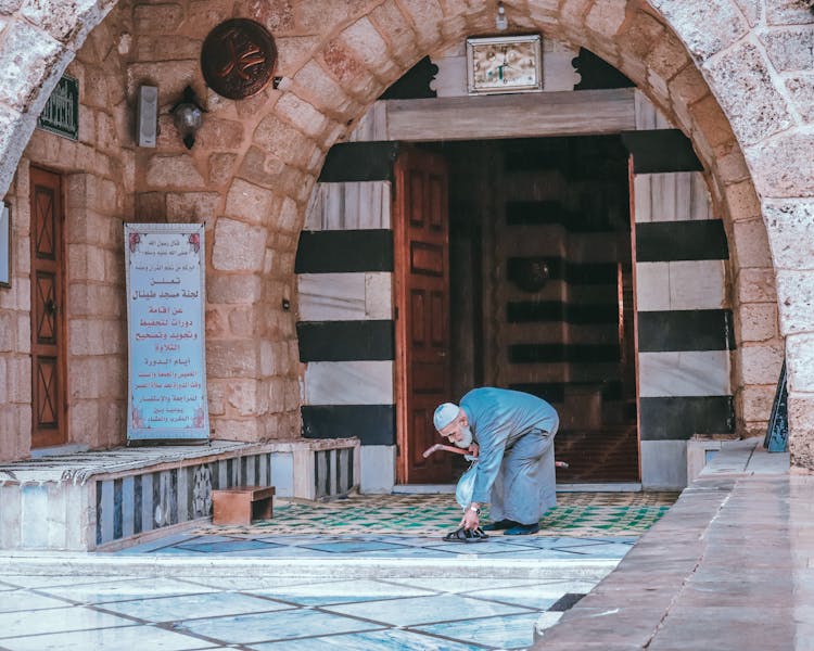 Man Leaving Shoes By Mosque Entrance