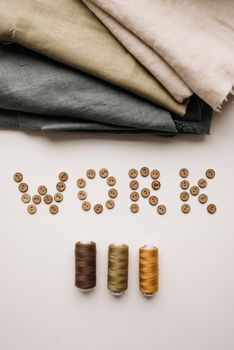 Artistic arrangement of sewing materials with 'work' spelled in buttons.