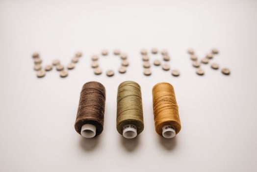 Artistic arrangement of sewing threads and buttons spelling 'work'. A still life that blends creativity and craft.