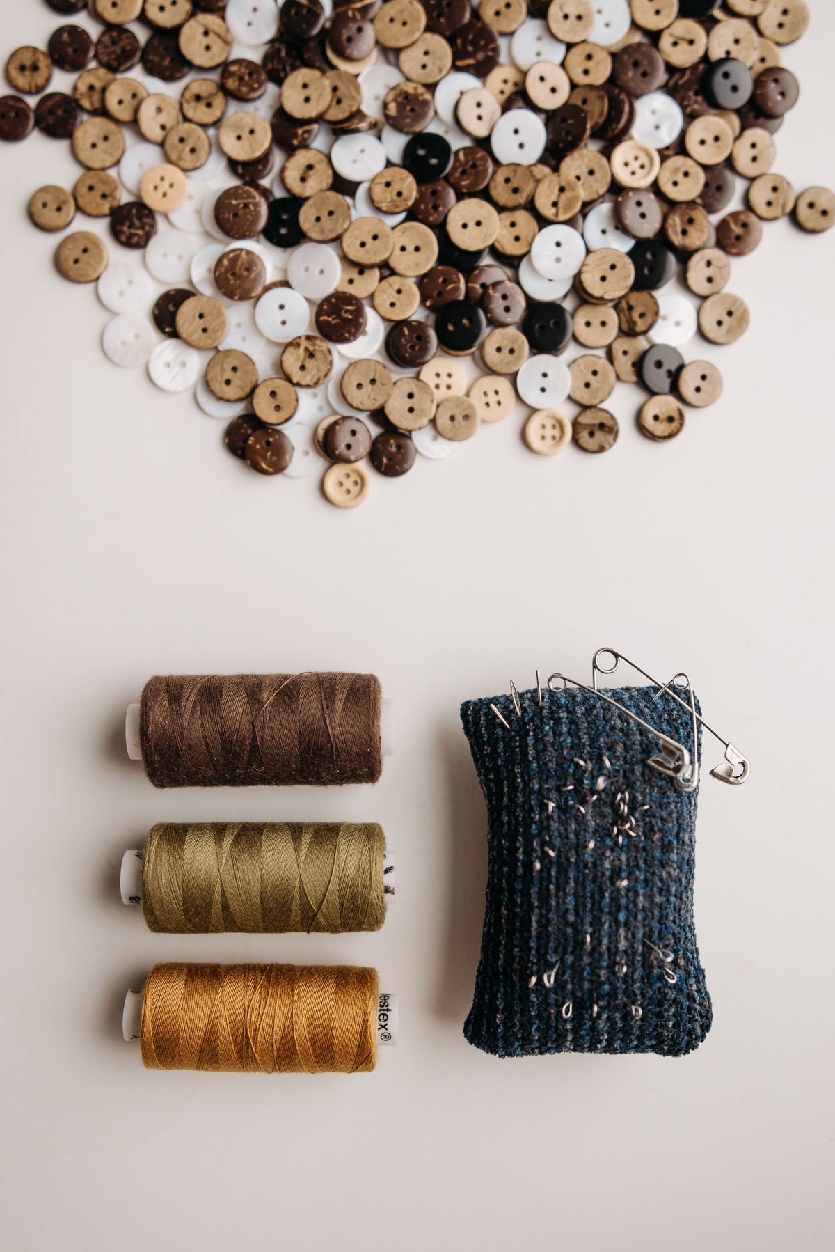 Stylish flat lay of sewing threads, assorted buttons, and a pin cushion