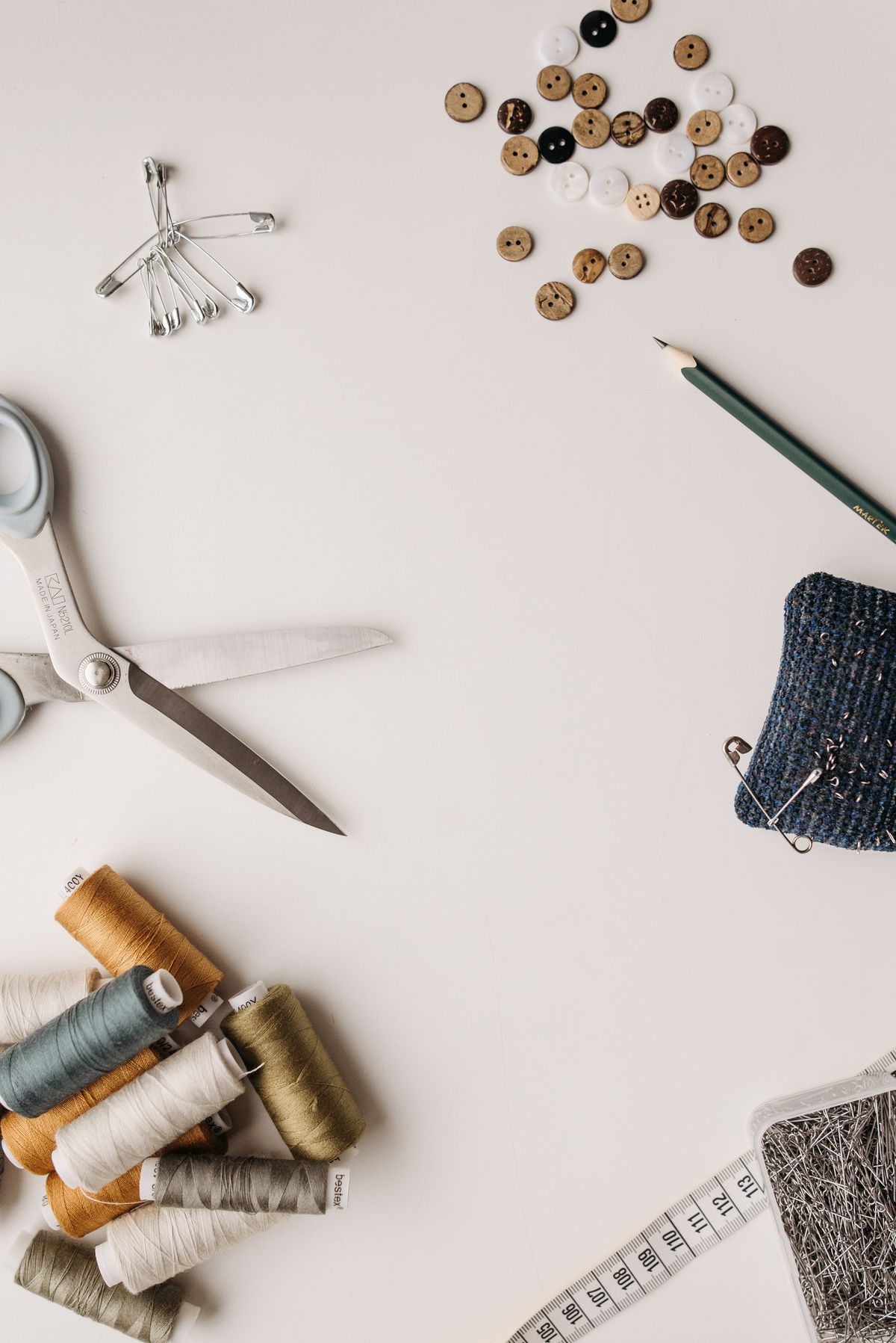Flat lay of sewing tools with buttons, threads, scissors, and a tape measure