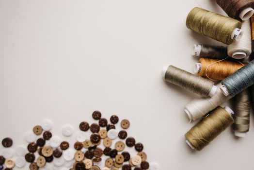 Assorted sewing threads and buttons arranged on a white surface, perfect for crafting and tailoring projects.