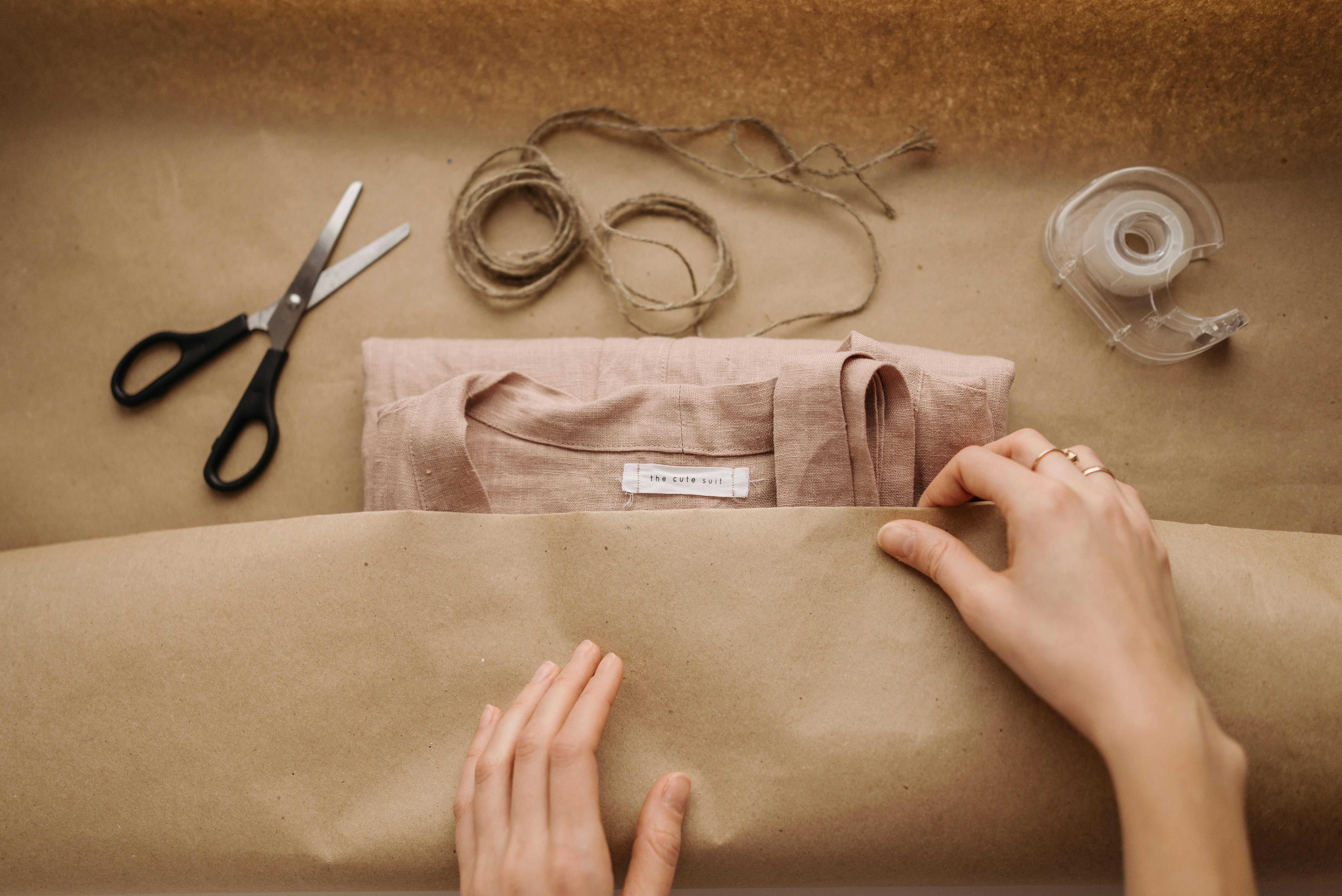 hands packing the shirt on brown paper