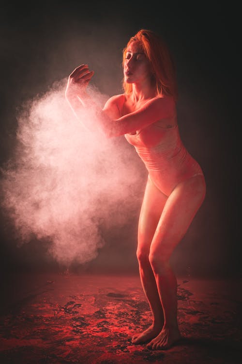 A Woman in a Bodysuit Blowing Powder