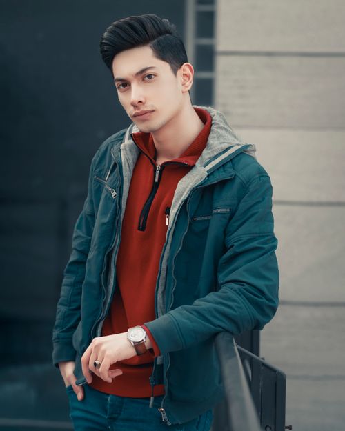 Free Portrait of a young man in a teal jacket and red sweater posing outdoors, Tabriz. Stock Photo